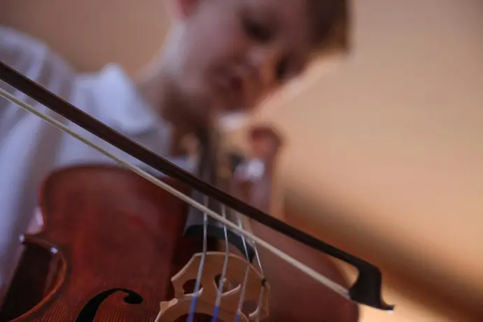 a young boy playing a violin in a room